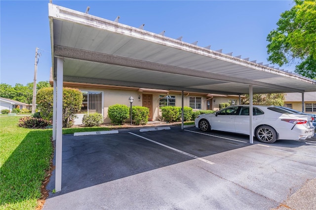 view of parking / parking lot with a carport and a yard