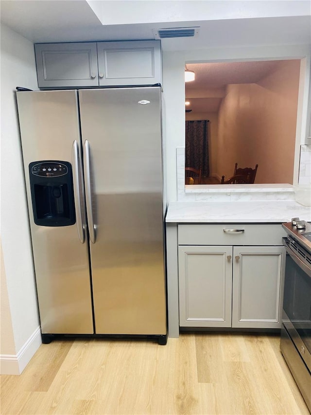 kitchen with stainless steel appliances, light hardwood / wood-style floors, and gray cabinetry