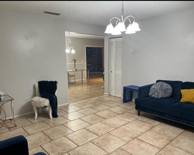 living room with a textured ceiling, a chandelier, and light tile flooring