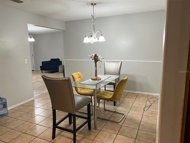 tiled dining room with a textured ceiling and a chandelier