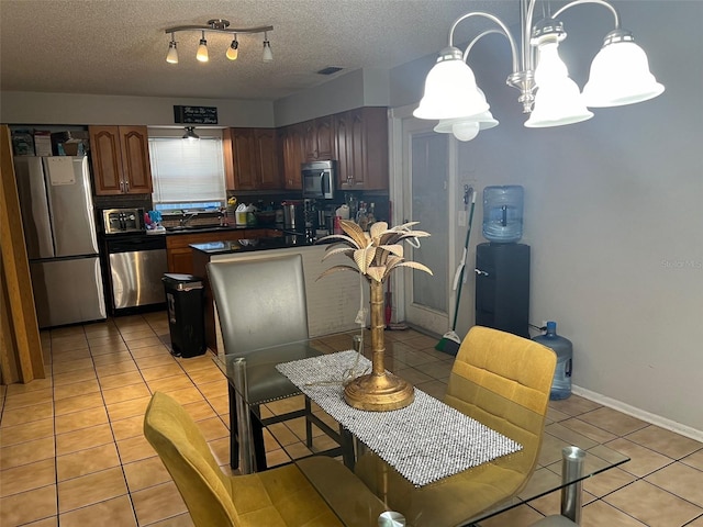 kitchen with backsplash, an inviting chandelier, appliances with stainless steel finishes, and light tile floors