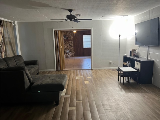 living room with ceiling fan, a textured ceiling, and wood-type flooring