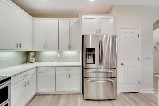 kitchen with tasteful backsplash, white cabinetry, light hardwood / wood-style floors, and stainless steel refrigerator with ice dispenser