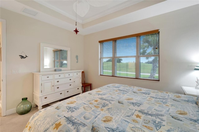 bedroom with ornamental molding, light colored carpet, ceiling fan, and a tray ceiling