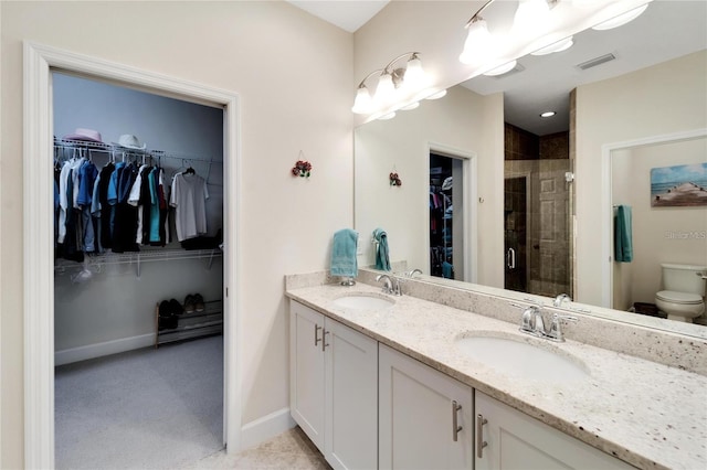 bathroom with double sink, tile floors, a shower with door, toilet, and large vanity