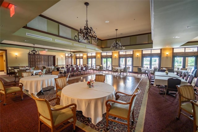 dining space with a chandelier, a towering ceiling, and french doors