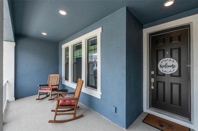 entrance to property with a porch and stucco siding