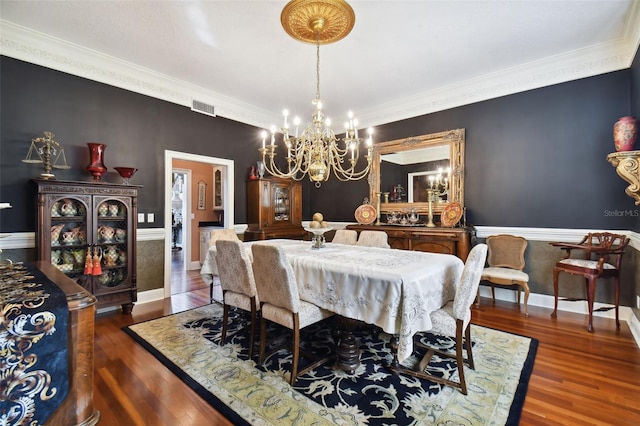 dining space featuring an inviting chandelier, ornamental molding, and dark hardwood / wood-style flooring