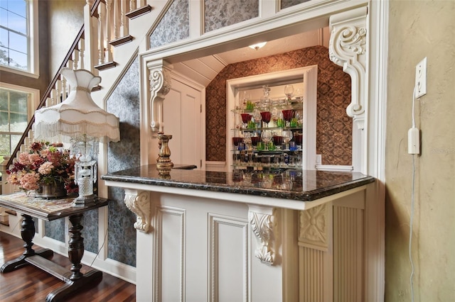 bar featuring dark stone countertops and wood-type flooring