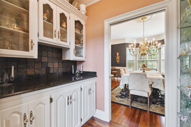 kitchen featuring dark stone countertops, backsplash, white cabinets, dark hardwood / wood-style flooring, and decorative light fixtures