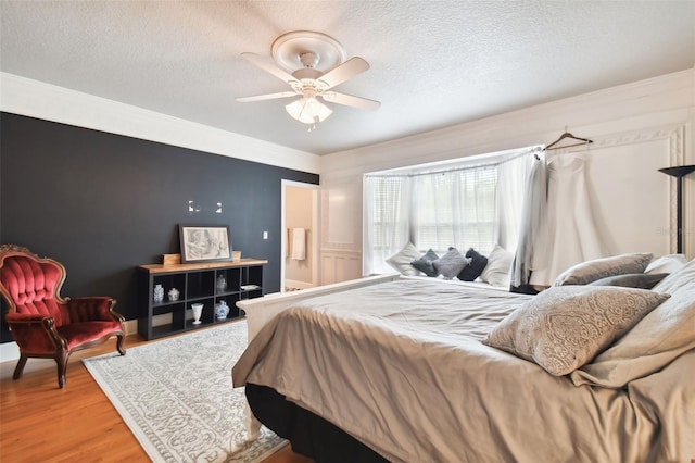 bedroom with hardwood / wood-style flooring, ceiling fan, and a textured ceiling