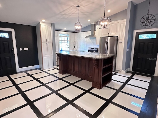 kitchen featuring wall chimney range hood, hanging light fixtures, stainless steel appliances, a center island, and decorative backsplash