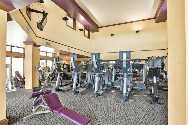 gym featuring a towering ceiling and carpet flooring