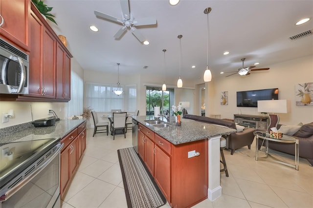 kitchen featuring appliances with stainless steel finishes, sink, pendant lighting, ceiling fan, and a center island with sink