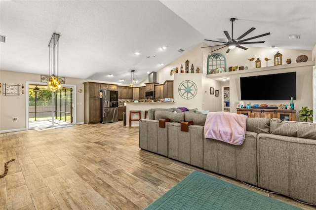 living room featuring a textured ceiling, light hardwood / wood-style flooring, high vaulted ceiling, and ceiling fan with notable chandelier