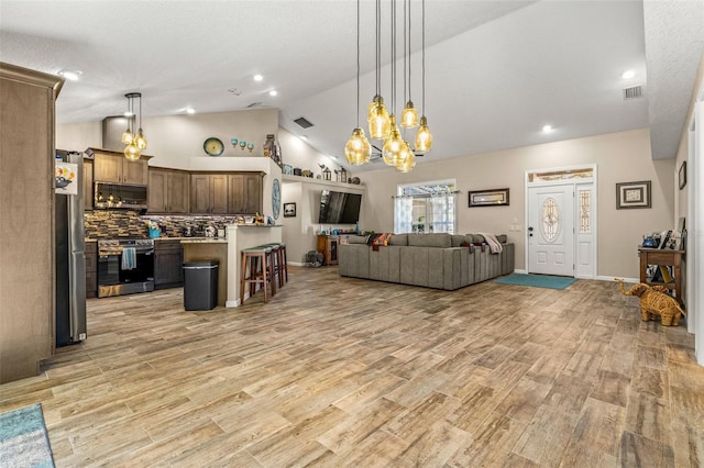 living room featuring an inviting chandelier, high vaulted ceiling, and light wood-type flooring