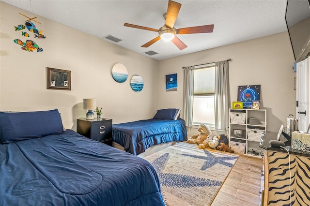 bedroom featuring light hardwood / wood-style floors, ceiling fan, and a textured ceiling