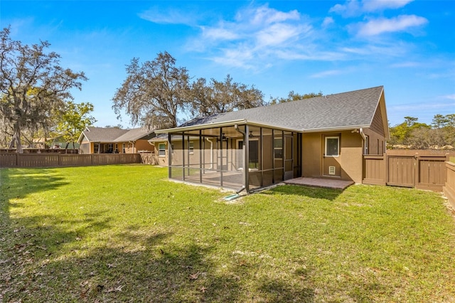 rear view of property featuring a yard, a sunroom, and a patio area