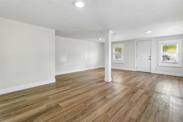 unfurnished room featuring hardwood / wood-style flooring, plenty of natural light, and decorative columns