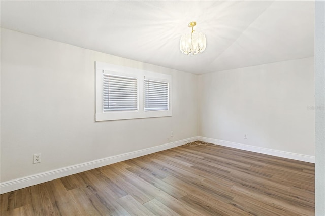 spare room featuring a chandelier and wood-type flooring