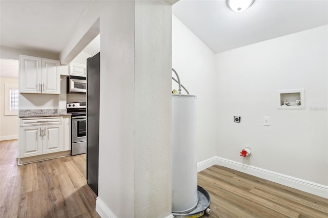 interior space with appliances with stainless steel finishes, light hardwood / wood-style flooring, white cabinets, and water heater