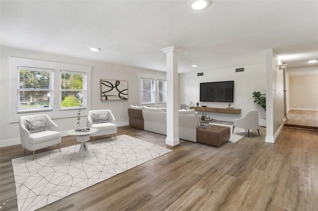 living room featuring light hardwood / wood-style floors and ornate columns