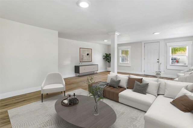 living room with a wealth of natural light, light hardwood / wood-style floors, and decorative columns