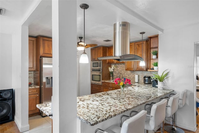 kitchen with pendant lighting, kitchen peninsula, island range hood, stainless steel appliances, and backsplash