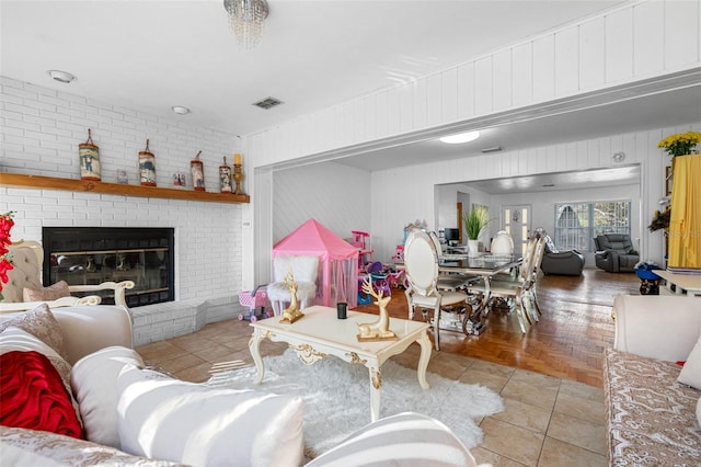 living room with brick wall, wooden walls, a fireplace, and light parquet floors