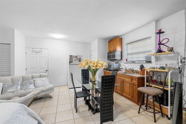 kitchen featuring light tile patterned floors, sink, and white fridge