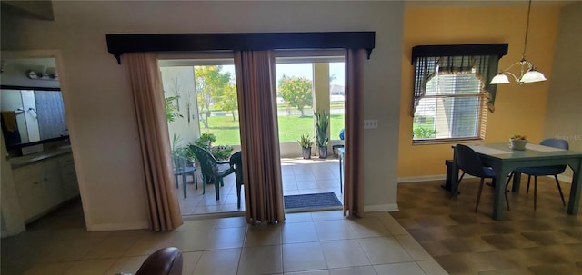 doorway to outside featuring light tile floors, plenty of natural light, and a chandelier