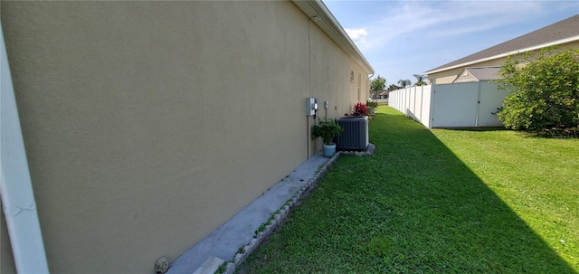 view of side of property featuring central air condition unit and a lawn