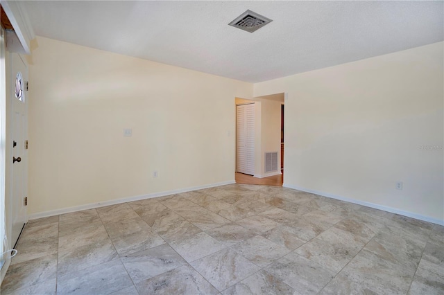 spare room featuring baseboards, visible vents, and a textured ceiling