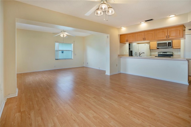 interior space featuring ceiling fan, stainless steel appliances, light countertops, light wood-style floors, and backsplash