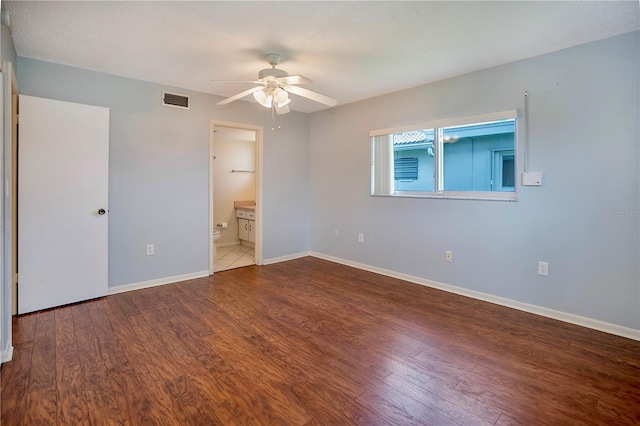 unfurnished bedroom with visible vents, wood finished floors, connected bathroom, baseboards, and ceiling fan