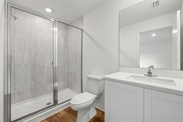 bathroom featuring toilet, large vanity, hardwood / wood-style floors, and walk in shower