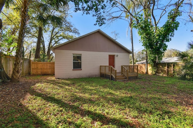 rear view of property featuring a wooden deck and a lawn