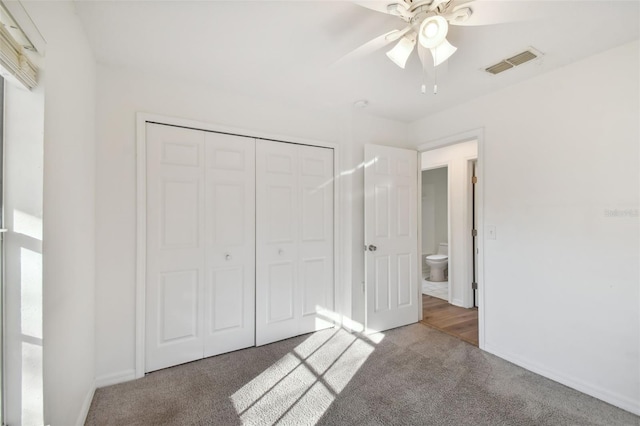 unfurnished bedroom with dark colored carpet, a closet, and ceiling fan