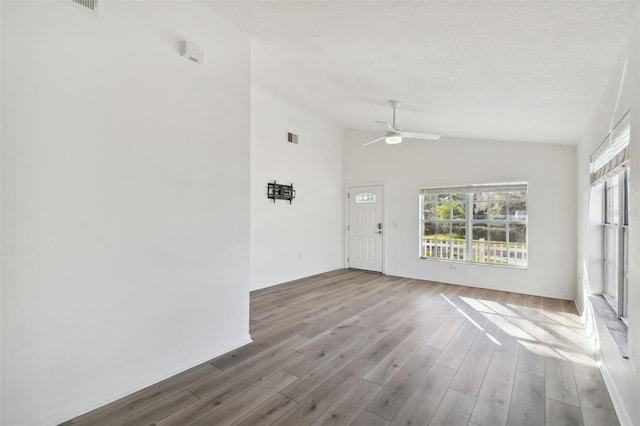 empty room featuring ceiling fan, vaulted ceiling, and light wood-type flooring