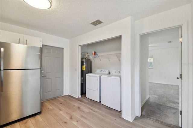 laundry area with light hardwood / wood-style flooring, separate washer and dryer, electric water heater, and a textured ceiling