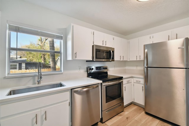 kitchen featuring white cabinets, sink, stainless steel appliances, and light hardwood / wood-style floors