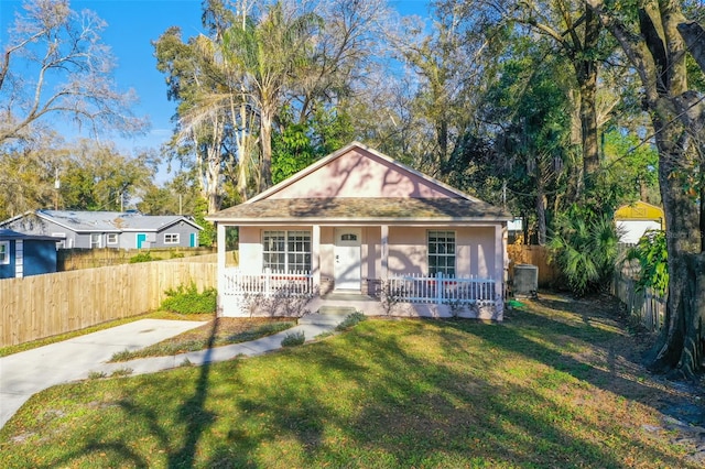 view of front of house featuring a front lawn, covered porch, and central AC unit