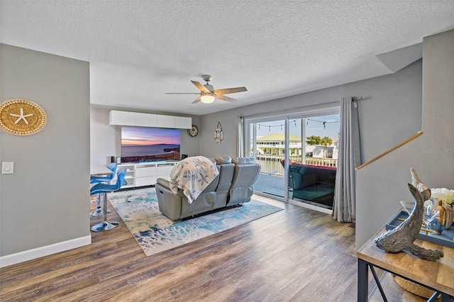 living room with hardwood / wood-style floors, ceiling fan, and a textured ceiling