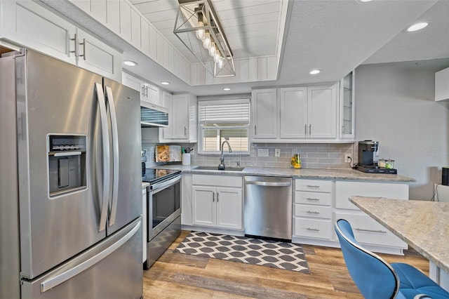 kitchen featuring white cabinets, sink, light wood-type flooring, light stone counters, and stainless steel appliances