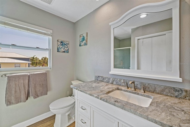 bathroom with hardwood / wood-style floors, vanity, toilet, a textured ceiling, and a shower with shower door