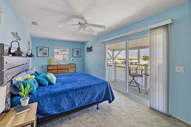 carpeted bedroom featuring a textured ceiling, access to exterior, ceiling fan, and multiple windows