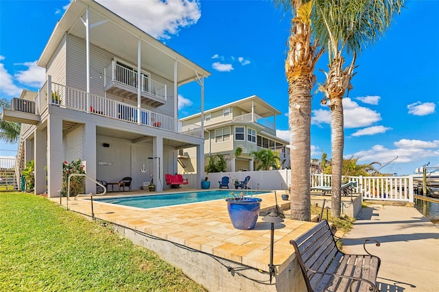 back of property featuring a fenced in pool, a balcony, and a patio