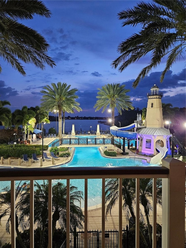 view of swimming pool featuring a water slide, a water view, and a patio