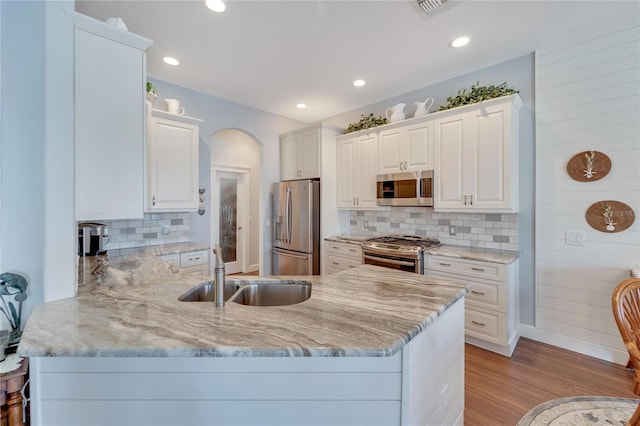 kitchen with white cabinets, appliances with stainless steel finishes, tasteful backsplash, and light hardwood / wood-style flooring