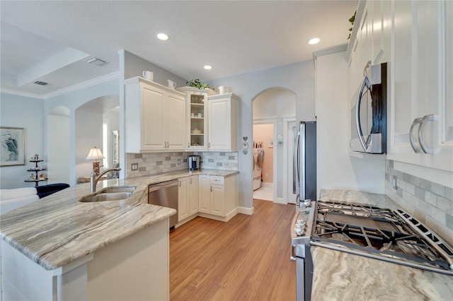 kitchen with appliances with stainless steel finishes, sink, tasteful backsplash, and kitchen peninsula